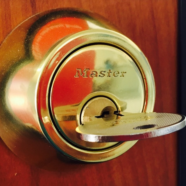 Close-up of a Master brass deadbolt lock cylinder with key inserted