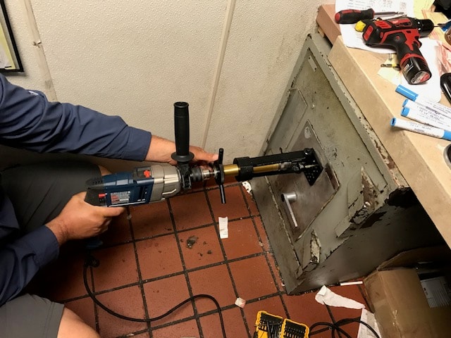 Technician drilling into a floor safe for non-destructive opening
